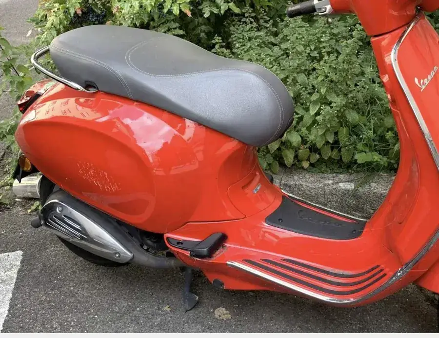 Orangefarbener Motorroller (Vespa) mit Sturzschäden